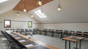 A conference room with long tables, chairs, and hanging pendant lights. - Luxury Home in Gouvy With Pool & Sauna (Gouvy)