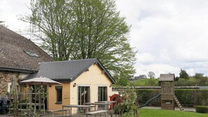 A small building with a sloped roof, outdoor seating area with benches and tables, and a wooden play structure. - Luxury Home in Gouvy With Pool & Sauna (Gouvy)