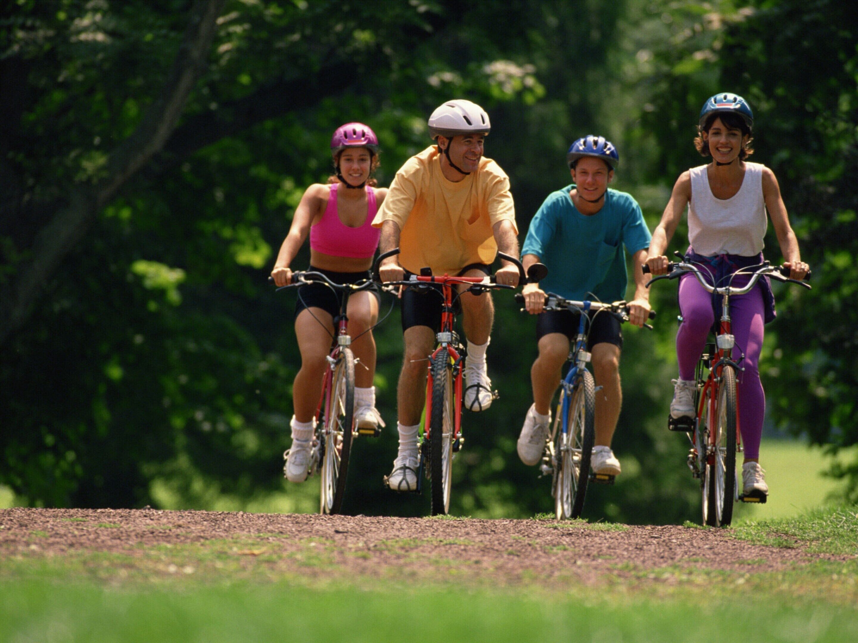 Quattro persone che vanno in bicicletta su un sentiero sterrato in un parco.