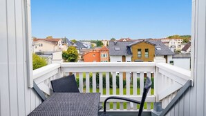 A balcony with a table and chairs, overlooking a residential area with various houses. - Apartment at the Rosenhof T301 - T301 (Kühlungsborn)