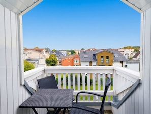 Un balcón con mesa y sillas, con vista a una zona residencial con varias casas.