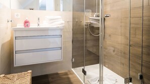 A modern bathroom with a glass shower enclosure, a white vanity with a mirror, and a wooden floor. - Apartment at the Rosenhof T301 - T301 (Kühlungsborn)