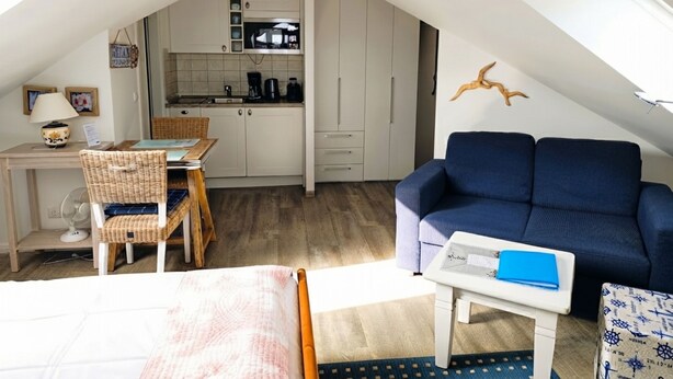 A compact living space with a kitchenette, a dining area, a sofa, and a bed. - Apartment at the Rosenhof T301 - T301 (Kühlungsborn)