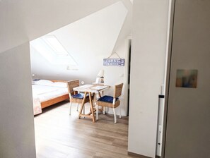 Un dormitorio con cama, una mesa y dos sillas. Hay un tragaluz sobre la cama y un cartel en la pared que dice 'RELAX THE 15 GOOD'.