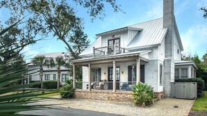 A two-story house with a covered porch, a chimney, and a well-maintained garden. - Ocean Oaks 19 - gorgeous home only a short walk to pool and beach (Jekyll Island)