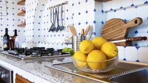 A kitchen with a granite countertop, a sink, and a bowl of lemons. There are hanging utensils and a wooden cutting board. - TRAMONTO: exclusive and panoramic apartment with sea-sunset view in Ischia (Forio)