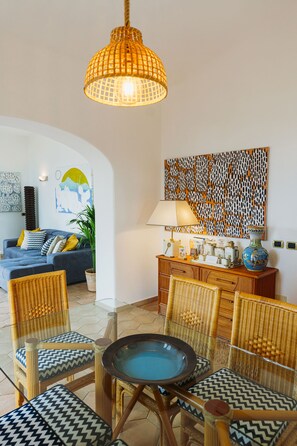 A room with a dining table, chairs, a sofa, a lamp, and a decorative wall piece. - TRAMONTO: exclusive and panoramic apartment with sea-sunset view in Ischia (Forio)