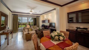 Amplia sala de estar con televisor grande, asientos cómodos y comedor con mesa dispuesta para cuatro.