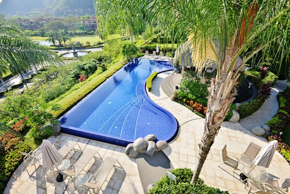 Relax by the serene pool surrounded by lush gardens and palm trees.
