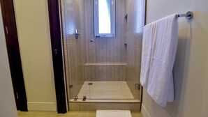 A small, tiled shower room with a window, a towel rack, and a bench. - Los Suenos Resort Miramar 5B (Jacó)