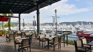 An outdoor seating area with tables and chairs, overlooking a marina with numerous boats. - Los Suenos Resort Del Mar 3C (Jacó)