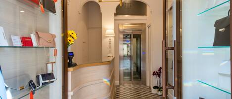 A hallway with glass display cases of handbags, a patterned floor, and a modern light fixture.