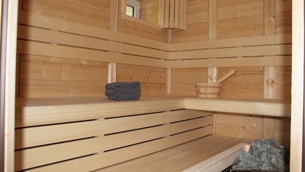 Un sauna avec des bancs en bois et une petite structure en bois.