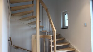 Un escalier en bois, doté d’une rampe et d’une petite fenêtre en haut.