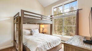 A bunk bed with a wooden frame, a bedside table with a lamp, and a window with a view of trees. - Luxury 3 Bedroom Townhouse next to Keystone Lake, Free Shuttle, Hot Tub and Sauna (Keystone)