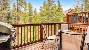 A wooden deck with a grill and chairs, surrounded by trees. - Luxury 3 Bedroom Townhouse next to Keystone Lake, Free Shuttle, Hot Tub and Sauna (Keystone)