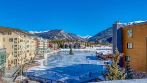 A hotel with multiple floors, a central courtyard with a frozen pond, and snow-covered mountains in the background. - Luxury 3 Bedroom Townhouse next to Keystone Lake, Free Shuttle, Hot Tub and Sauna (Keystone)