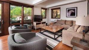 Ein modernes Wohnzimmer mit einer Couch, Sesseln, einem Couchtisch und einem Fernseher.