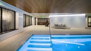 An indoor swimming pool with a wooden ceiling, a seating area with cushions, and a clear path leading to the pool. - Vail Lion Studio Mountain Vacation Rental Just Steps From the Eagle Bahn Gondola (Vail)