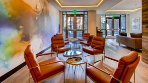 A modern lobby with leather chairs, a coffee table, and a colorful abstract wall. - Vail Lion Studio Mountain Vacation Rental Just Steps From the Eagle Bahn Gondola (Vail)