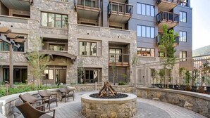 A courtyard with a fire pit, outdoor seating, and a stone wall. - Vail Lion Studio Mountain Vacation Rental Just Steps From the Eagle Bahn Gondola (Vail)
