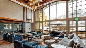 A spacious lounge area with comfortable seating, large windows, and a fireplace. - Platinum Vail Ritz-carlton 3 Bedroom Mountain Residence Just One Block From the Eagle Bahn Gondola (Vail)