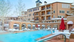 A hotel with a pool area, outdoor seating, and a multi-story building with balconies. - 2 Bedroom Ski-in Ski-out Condo in Snowmass Village (Snowmass Village)