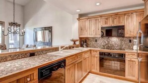 Eine Küche mit Holzausstattung, Granit Arbeitsplatten, einem Geschirrspüler, einem Backofen und einem Edelstahl-Kühlschrank.