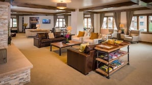 A spacious living room with a fireplace, leather sofas, a coffee table, and a bookshelf.