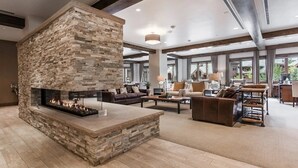 A spacious living area with a stone fireplace, comfortable seating, and large windows offering views of the outdoors.