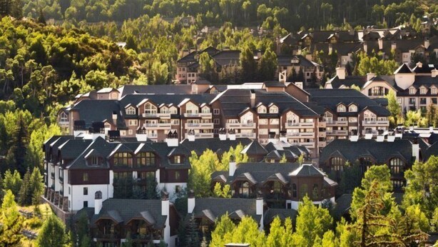 A cluster of chalet-style buildings with multiple stories, surrounded by dense forest.