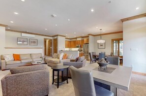 A spacious living area with a dining table, sofas, and a kitchen in the background.