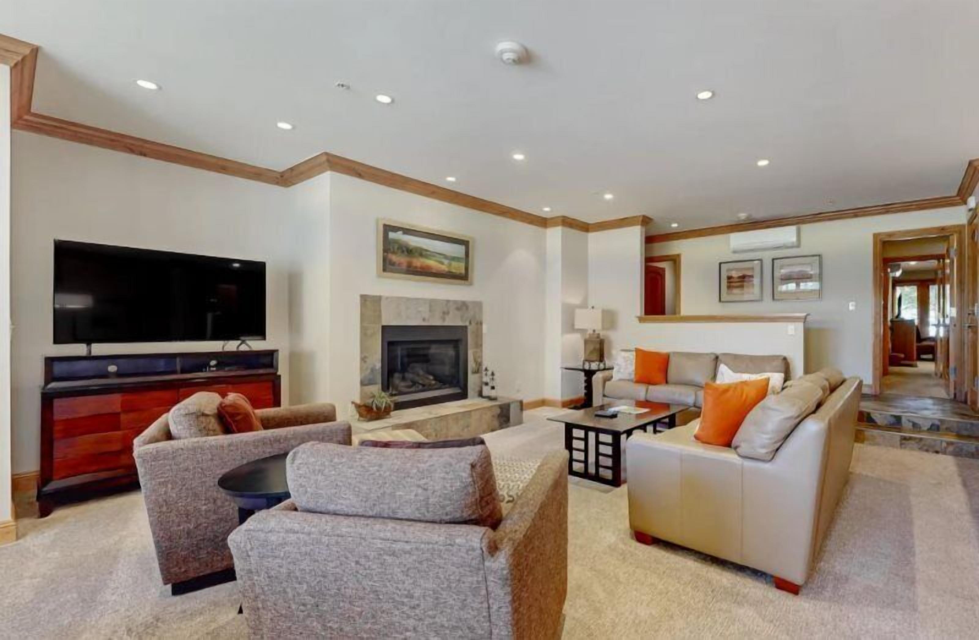 A spacious living room with a fireplace, a television, and comfortable seating.