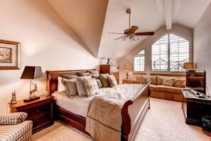 Une chambre avec un grand lit, un ventilateur de plafond, un canapé et un bureau.
