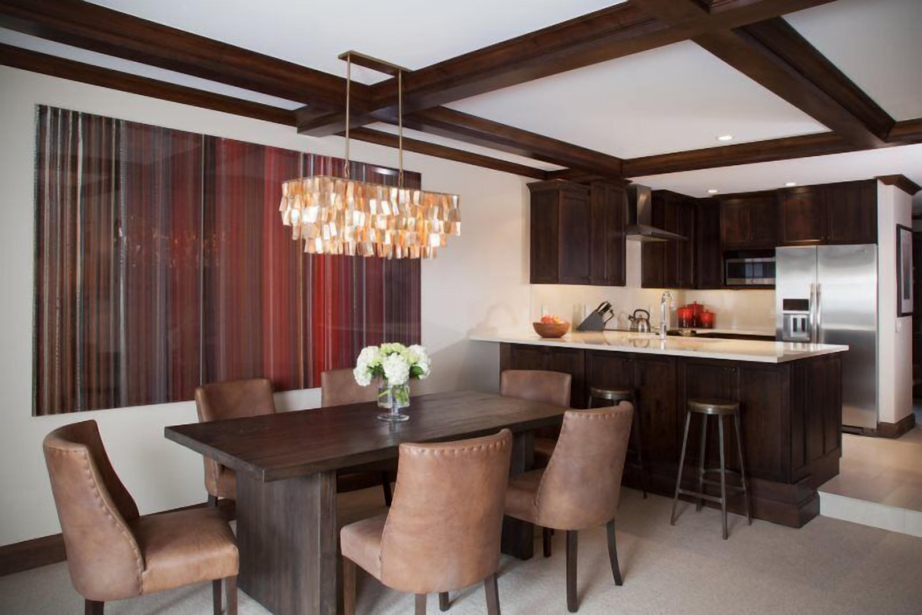 Una cocina moderna con armarios de madera oscura, una isla central con taburetes, una lámpara colgante y un adorno de pared a rayas.