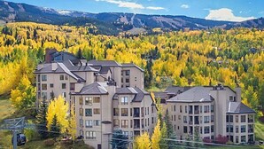 Ein mehrstöckiges Hotel mit modernem Design, gelegen in einer bergigen Landschaft mit Herbstlaub.