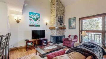 A living room with a stone fireplace, a television, and a painting on the wall.