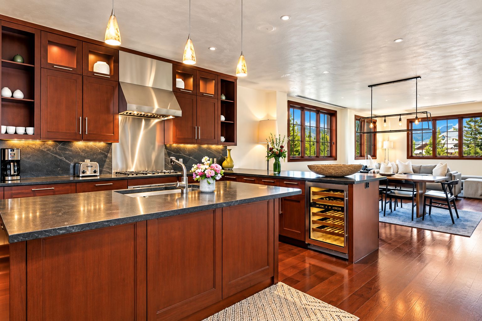 Una cocina moderna con una isla central, armarios de madera e iluminación colgante.