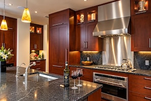 A modern kitchen with dark wood cabinets, stainless steel appliances, and pendant lighting. - Platinum Vail Solaris 3 Bedroom Vacation Rental Set at the Base of the Mountain Just Steps From the Gondola (Vail)