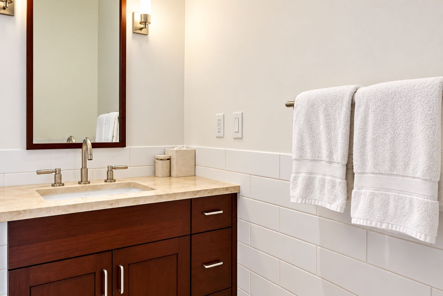 A bathroom with a sink, mirror, towel rack, and wooden cabinets.