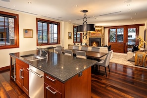 A spacious kitchen with a large island, wooden cabinetry, and a stone accent wall. - Platinum Vail Solaris 3 Bedroom Vacation Rental Set at the Base of the Mountain Just Steps From the Gondola (Vail)