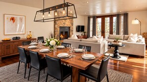 A modern dining area with a wooden table set for six, flanked by black chairs, a fireplace, and a stone accent wall. - Platinum Vail Solaris 4 Bedroom Vacation Rental Set at the Base of the Mountain Just Steps From the Gondola (Vail)