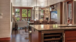 Een moderne keuken met een groot eiland, hanglampen en uitzicht op de omgeving.