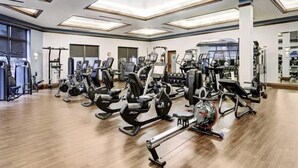 Un gimnasio amplio con numerosas máquinas de cardio, estaciones de pesas y diversos equipos de ejercicio.