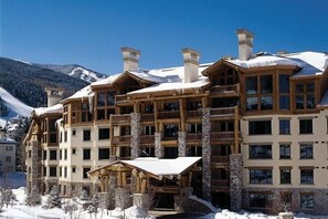 Eine mehrstöckige Lodge mit Holzfassade und mehreren Balkonen, umgeben von schneebedeckten Bergen.