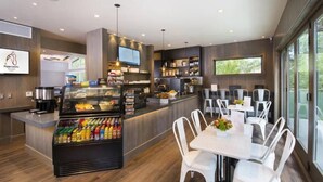 Un restaurant moderne doté d’un comptoir, d’un espace salon et d’une grande fenêtre.