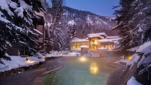 Un complexe hôtelier doté d’une piscine chauffée, entouré d’arbres couverts de neige et offrant une vue sur les montagnes.