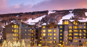 A multi-story hotel with a stone facade, multiple balconies, and warm interior lighting. - Vail Lion 1 Bedroom Mountain Vacation Rental Just Steps From the Eagle Bahn Gondola (Vail)