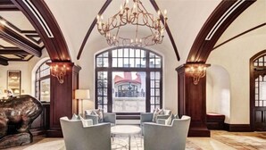 Um hall espaçoso com teto alto, grandes janelas e um candelabro.