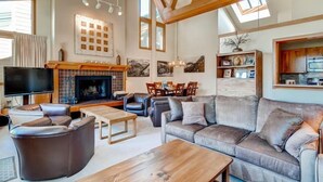 A spacious living room with a fireplace, leather sofas, a wooden coffee table, and a television. - Lakeside Village 4 Bedroom Condo (Keystone)